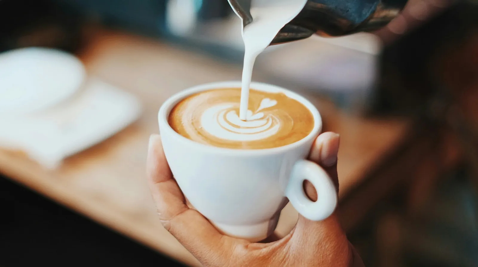 Barista heller melk i en kopp