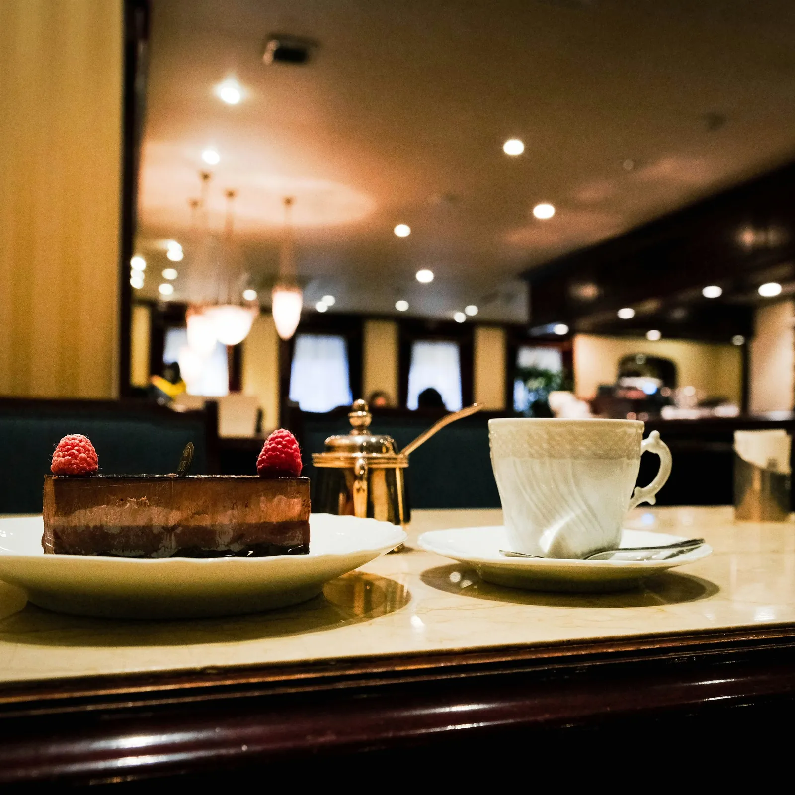 Sjokoladekake med bringebær og en kopp kaffe på marmorbord